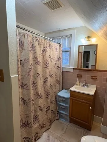 a bathroom with a sink toilet a mirror and shower curtain