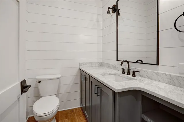 a bathroom with a granite countertop sink toilet and mirror