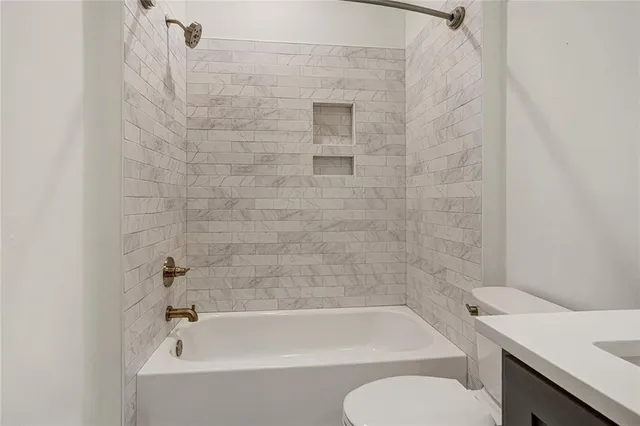 a bathroom with a bathtub shower sink vanity and toilet