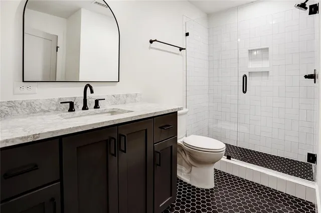 a bathroom with a sink a toilet a mirror and shower