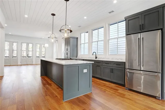 a kitchen with stainless steel appliances granite countertop a refrigerator a sink dishwasher a kitchen island a stove and a wooden floors