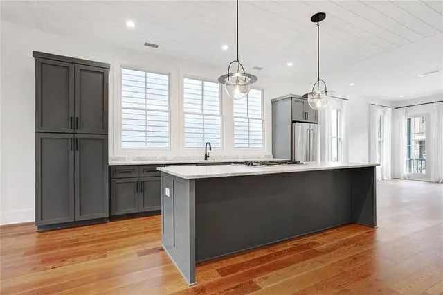 a kitchen with granite countertop a refrigerator a sink and wooden floors