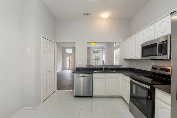 a large white kitchen with stainless steel appliances granite countertop a stove and a sink