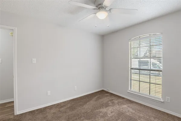 an empty room with a ceiling fan and carpet