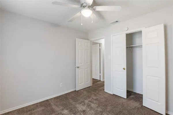 an empty room with closet and a chandelier fan