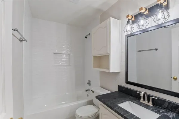 a bathroom with a granite countertop sink a toilet and bathtub