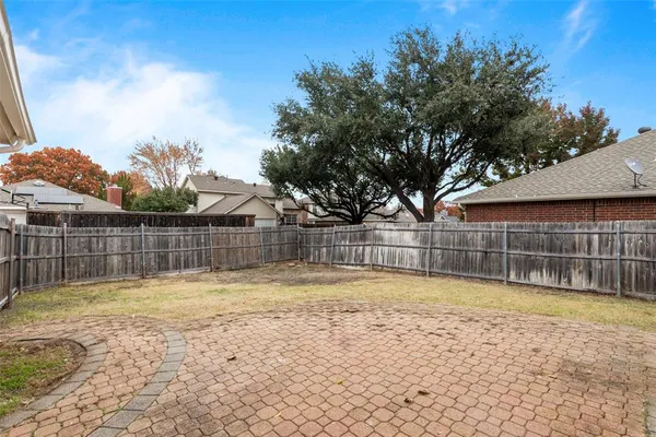 a view of a brick house next to a yard with large trees