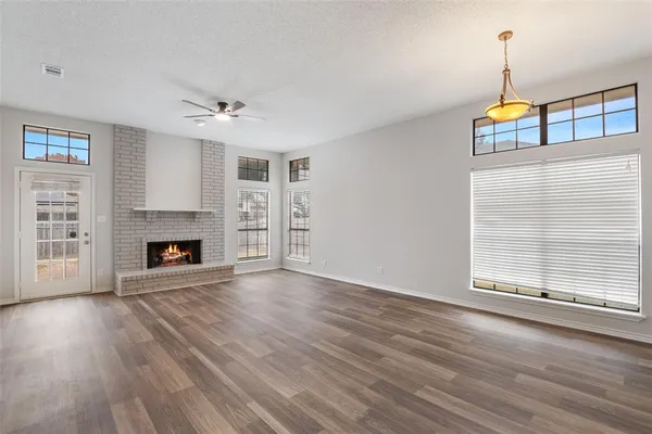 a view of an empty room with wooden floor fireplace and a window