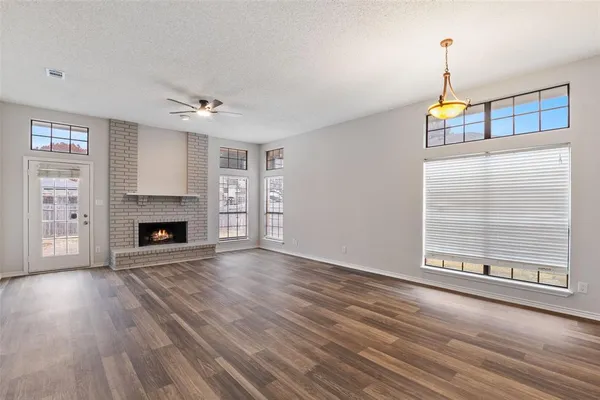 wooden floor fireplace and windows in an empty room