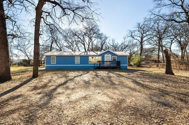 a front view of house with yard and covered with trees