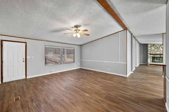 an empty room with wooden floor chandelier fan and windows