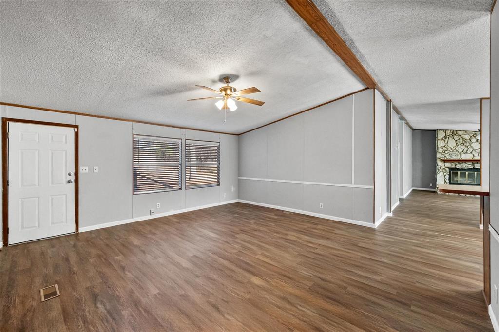 7634 Gibson Cemetery Road Mansfield, TX 76063 - Photo 3 of 11 an empty room with wooden floor chandelier fan and windows