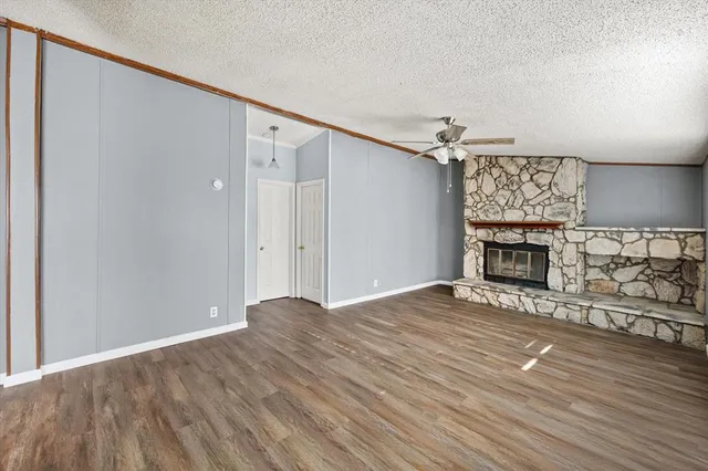 a view of an empty room with wooden floor fireplace and a window