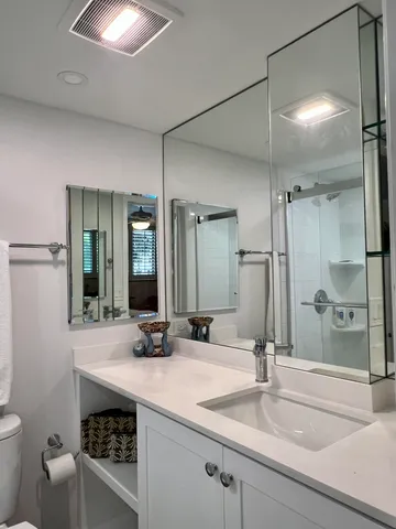 a bathroom with a sink a toilet a mirror and shower