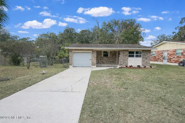 a front view of house with yard and trees in the background