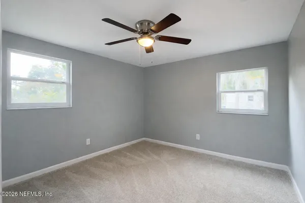 an empty room with a window and a ceiling fan