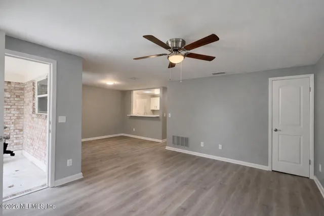 an empty room with wooden floor and windows