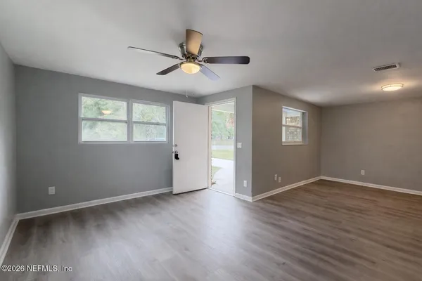 a view of an empty room with wooden floor and a window