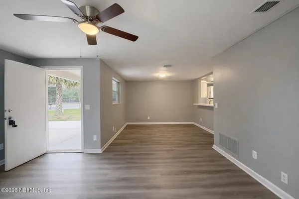 a view of an empty room with wooden floor and a window