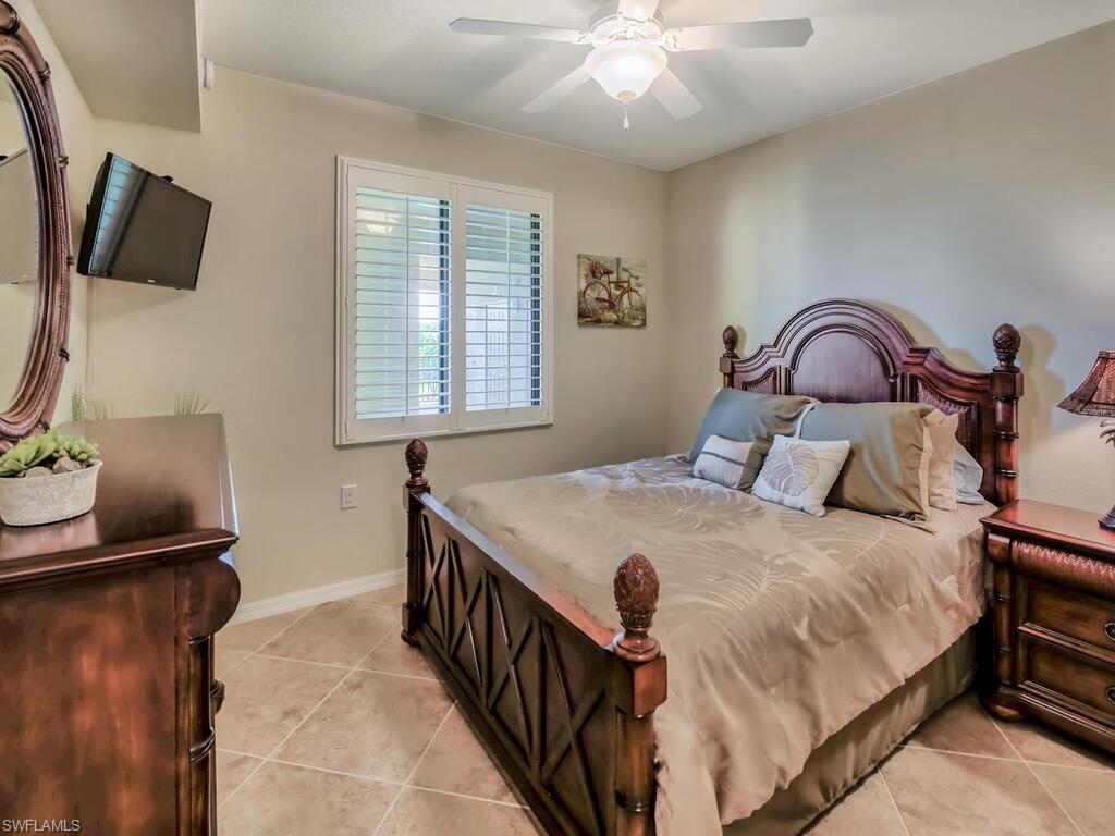 9735 Acqua Court, Unit 635 Naples, FL 34113 - Photo 14 of 33 a bedroom with a bed and a flat tv screen on the dresser