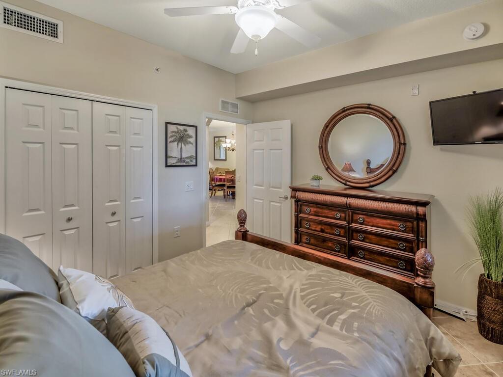 9735 Acqua Court, Unit 635 Naples, FL 34113 - Photo 15 of 33 a bedroom with a bed and a chandelier