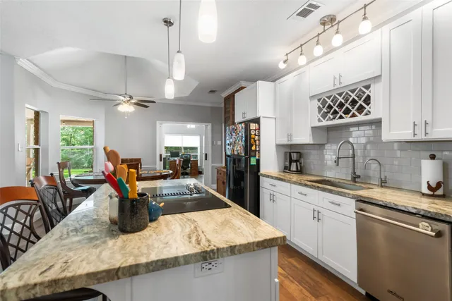 a kitchen with stainless steel appliances granite countertop a sink dishwasher a stove top oven a dining table and chairs with wooden floor