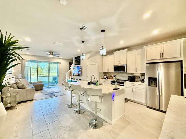 a large white kitchen with a large window and stainless steel appliances