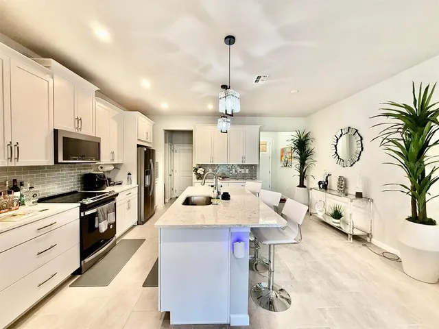 a large white kitchen with a stove a sink dishwasher and a dining table with kitchen countertops