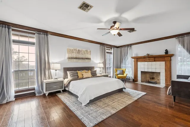a bedroom with a bed a chair and a dresser with wooden floor