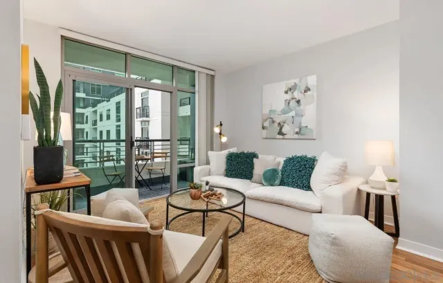 a living room with furniture large windows and wooden floor