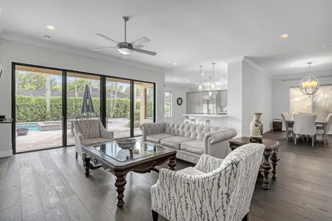 a kitchen with stainless steel appliances kitchen island granite countertop a stove a sink a refrigerator and white cabinets with wooden floor