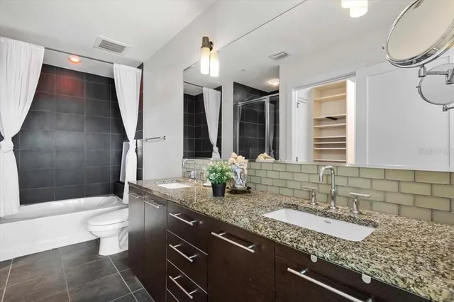 a bathroom with a granite countertop sink a toilet a mirror and shower