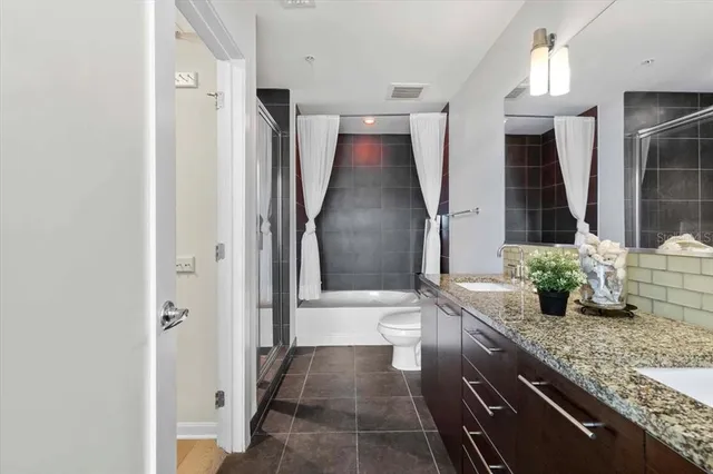 a bathroom with a granite countertop sink a toilet and shower