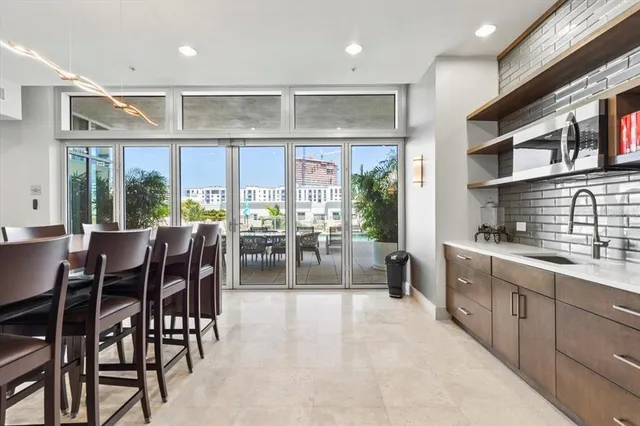 a dining hall with stainless steel appliances granite countertop a stove a sink a dining table and chairs