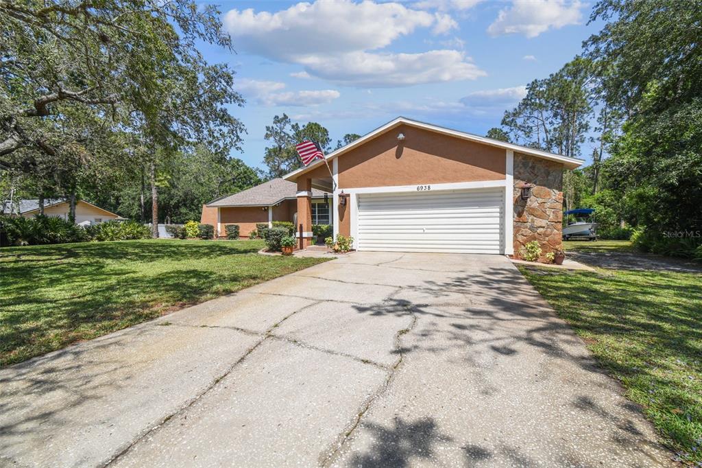 6938 Coronet Drive New Port Richey, FL 34655 - Photo 2 of 49 a view of house with garden and tall trees