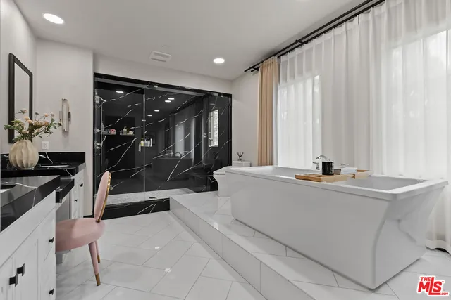 a spacious en suite bathroom with a granite countertop sink and a mirror