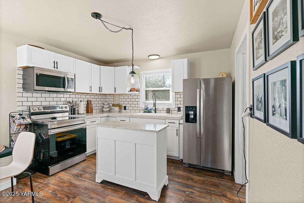 1506 South 2nd Avenue Yakima, WA 98902 - Photo 8 of 28 a kitchen with stainless steel appliances a stove a sink dishwasher a refrigerator white cabinets and wooden floor