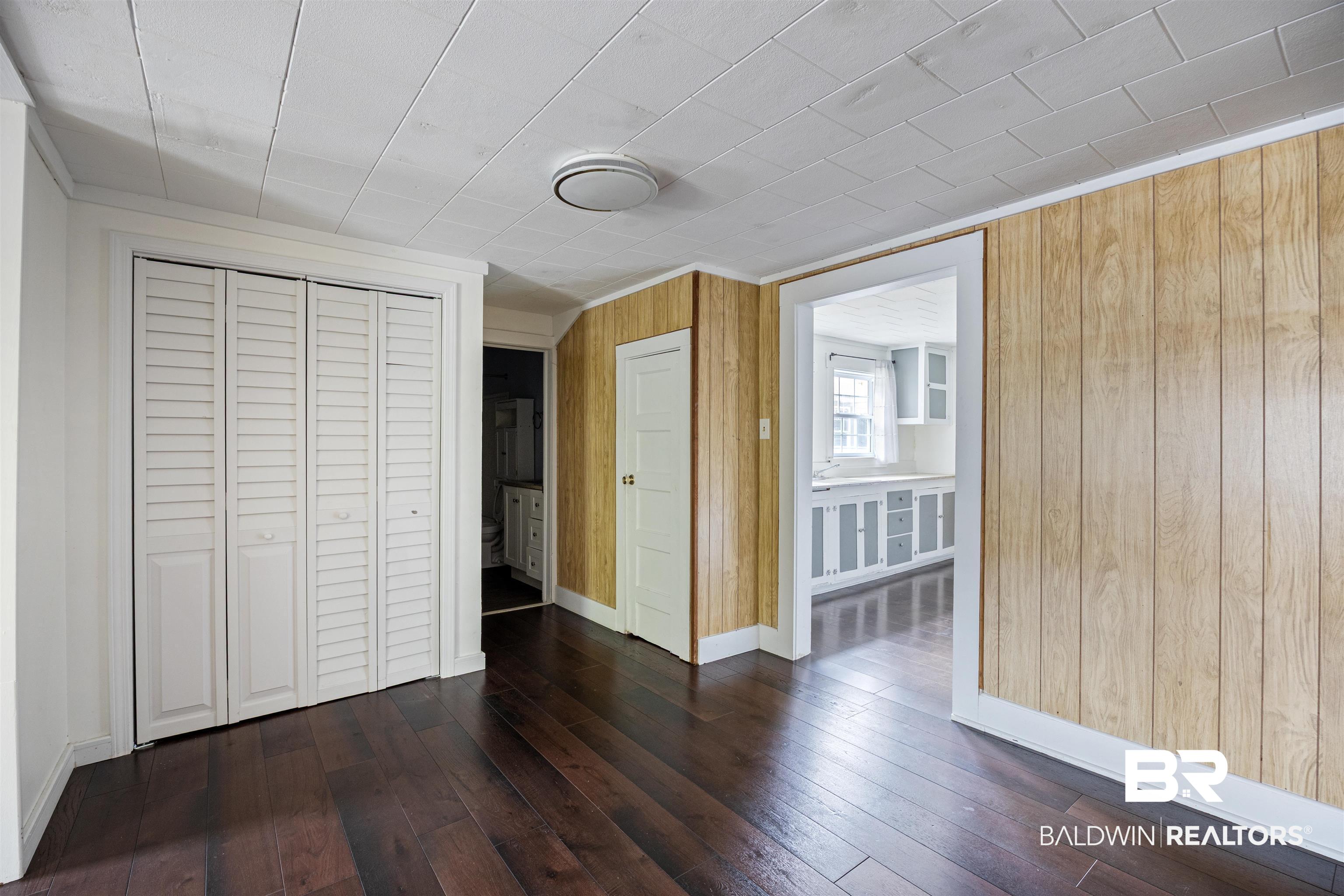 112 South Juniper Street Foley, AL 36535 - Photo 15 of 64 Unfurnished bedroom with a closet, dark wood finished floors, and wood walls