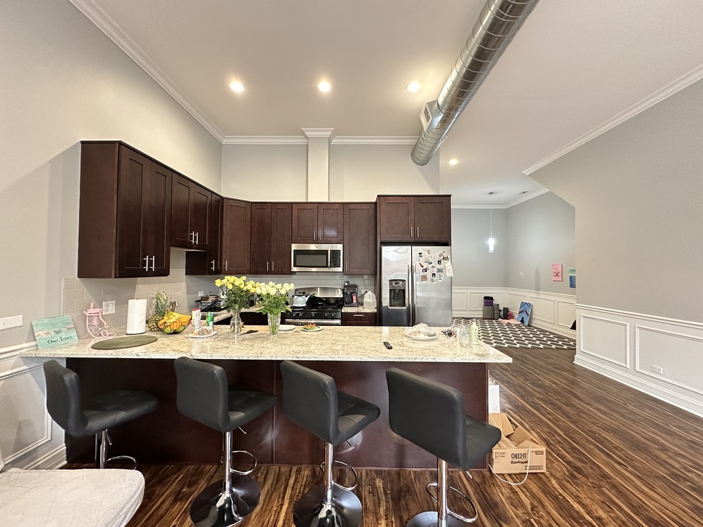 3336 West Irving Park Road, Unit 1 Chicago, IL 60618 - Photo 2 of 20 a kitchen with stainless steel appliances kitchen island granite countertop a dining table and chairs