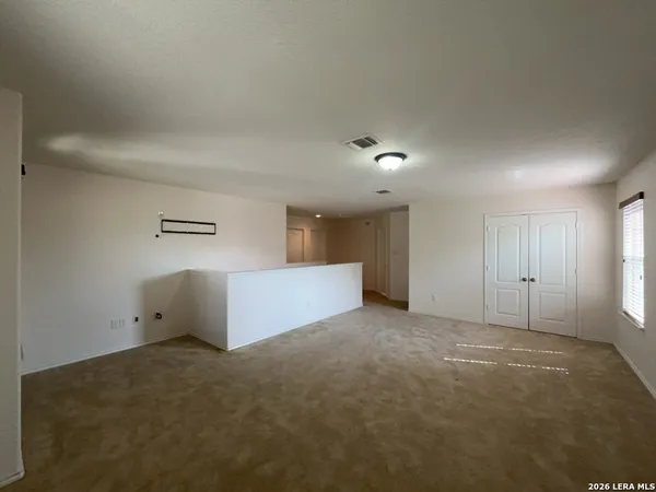 an empty room with a fan & a chandelier fan