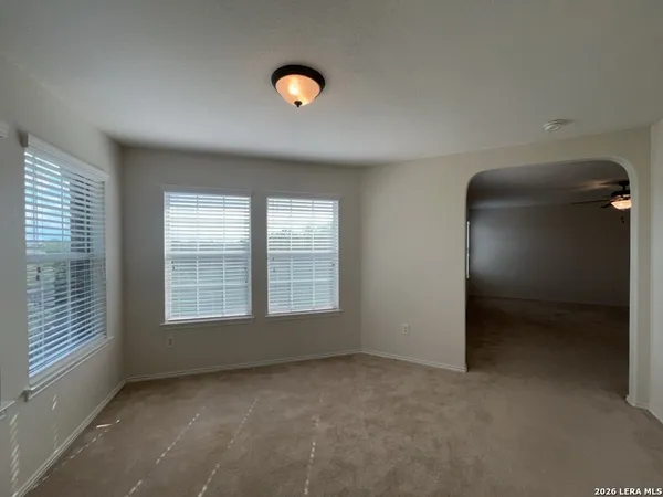 en empty room with windows and chandelier fan
