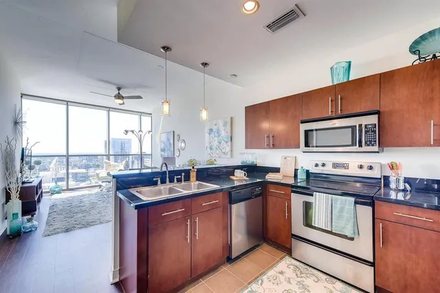 a kitchen with stainless steel appliances kitchen island granite countertop a sink and a refrigerator