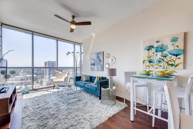 a living room with furniture a flat screen tv and a floor to ceiling window
