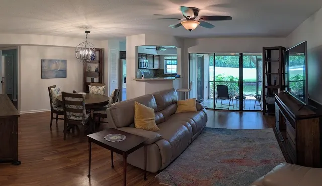 a living room with furniture a ceiling fan and a flat screen tv