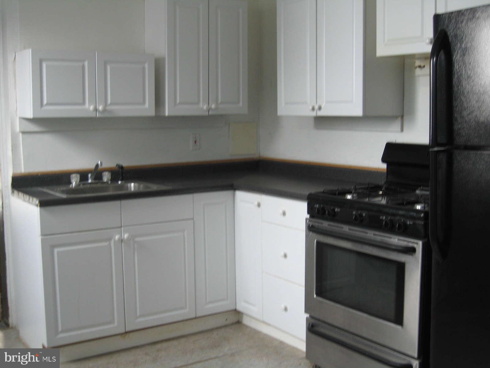 1415 Riverside Avenue Baltimore, MD 21230 - Photo 3 of 24 a kitchen with granite countertop white cabinets and black appliances