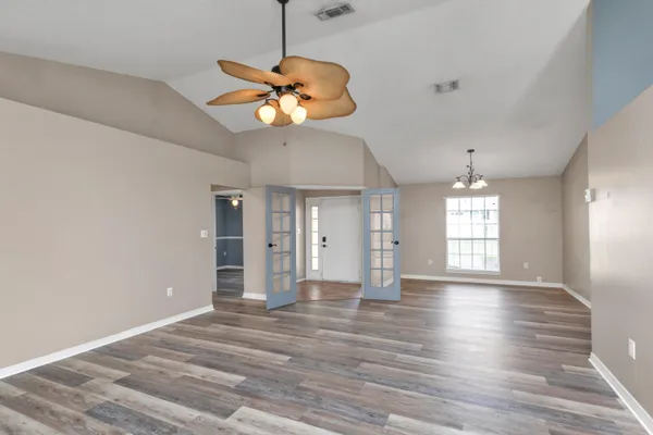 a view of an empty room with window and wooden floor