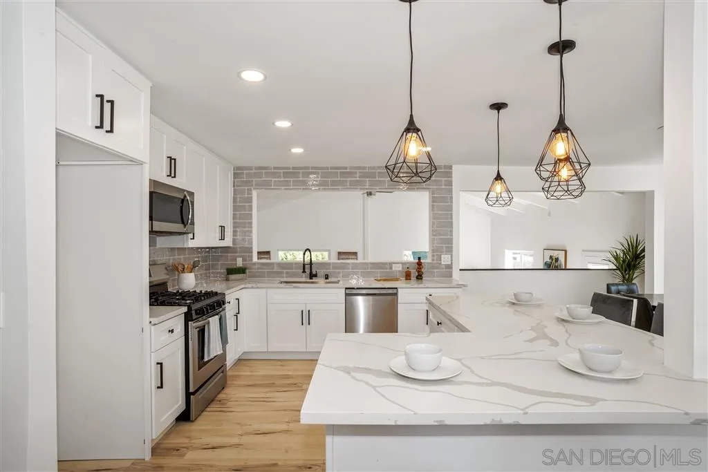 751 Crestview Road Vista, CA 92081 - Photo 8 of 24 a kitchen with stainless steel appliances kitchen island granite countertop a stove a sink and white cabinets