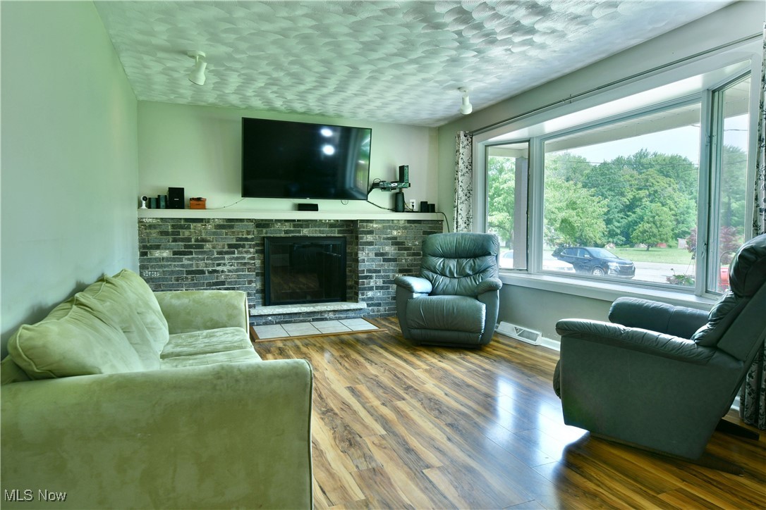 2847 Selkirk Bush Road Warren, OH 44481 - Photo 5 of 47 Living area featuring wood finished floors, a brick fireplace, and a textured ceiling