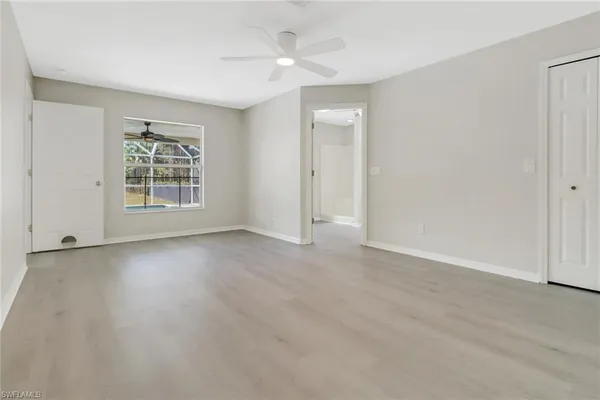 a view of an empty room with a window and wooden floor