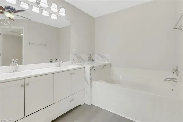a spacious bathroom with a double vanity sink mirror and bathtub
